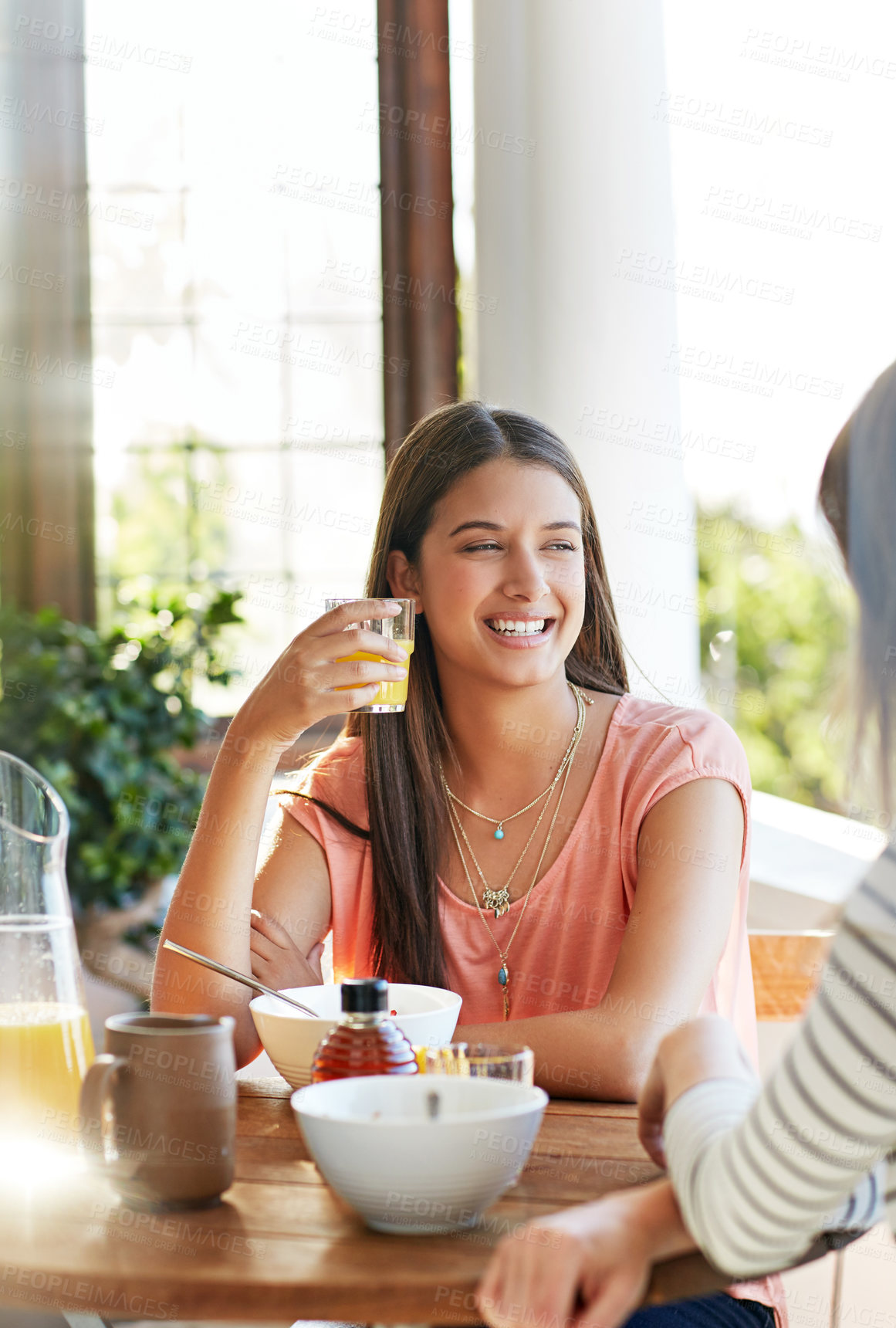 Buy stock photo Shot of two friends eating breakfast together on a balcony