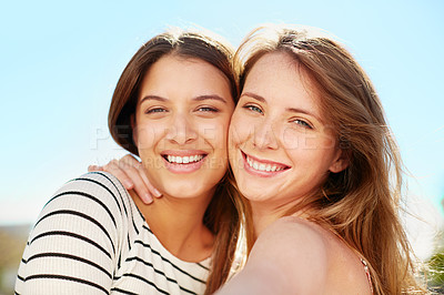 Buy stock photo Portrait of two young friends hugging while enjoying a day outside together