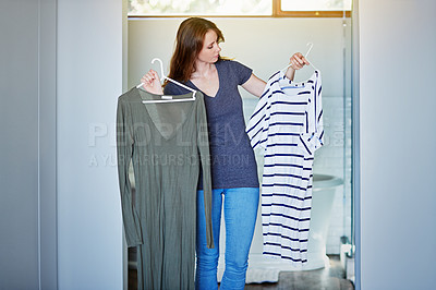 Buy stock photo Shot of a young woman standing in her bathroom choosing outfits