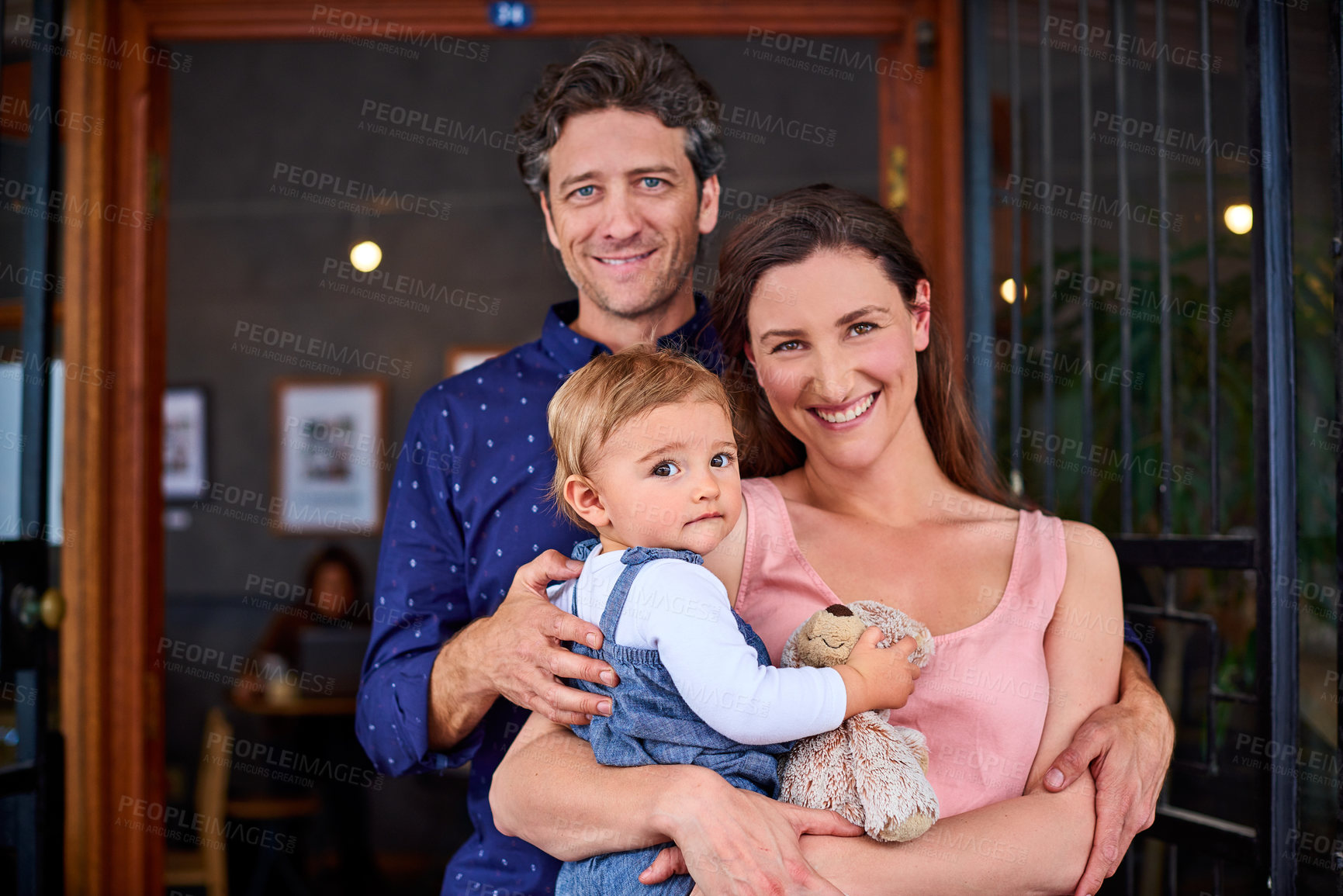 Buy stock photo Portrait of smiling couple and their little girl standing in front of their bakery