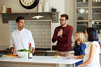 Buy stock photo Shot of a group of friends talking and drinking wine together while preparing dinner