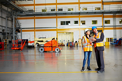 Buy stock photo Shot of two warehouse workers talking together over a digital tablet
