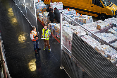 Buy stock photo High angle shot of two warehouse workers standing in a large warehouse
