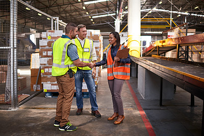 Buy stock photo Shot of two workers shaking hands together while standing in a large warehouse