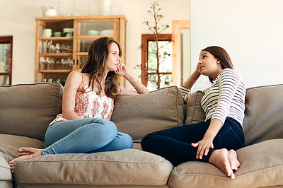 Buy stock photo Shot of two friends talking together while sitting on the sofa at home