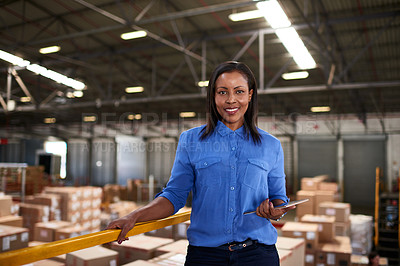 Buy stock photo Portrait of a smiling worker holding a digital tablet while standing in a large warehouse full of boxes