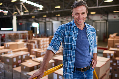 Buy stock photo Portrait of a smiling worker standing in a large warehouse full of boxes