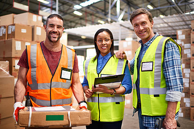 Buy stock photo Portrait of a group of smiling coworkers standing in a large warehouse full of boxes