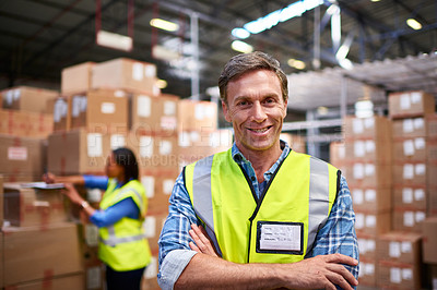 Buy stock photo Portrait of a worker standing in a large warehouse full of boxes with a colleague in the background
