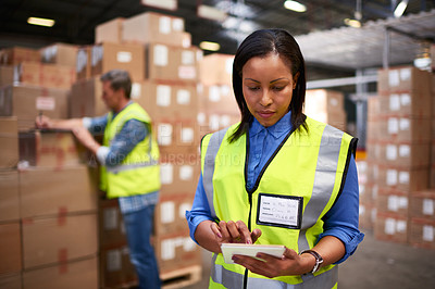 Buy stock photo Shot of a worker using a digital tablet in a large warehouse full of boxes with a colleague in the background
