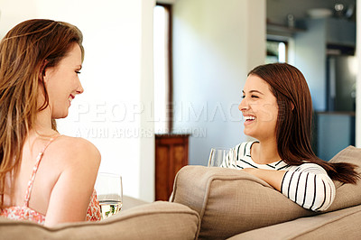 Buy stock photo Shot of two young friends talking and drinking wine while relaxing on the sofa