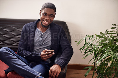 Buy stock photo Portrait of a smiling young man sitting in an office using a cellphone