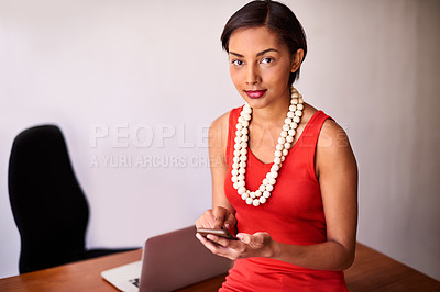 Buy stock photo Portrait of a young woman using a cellphone while sitting on her desk in an office