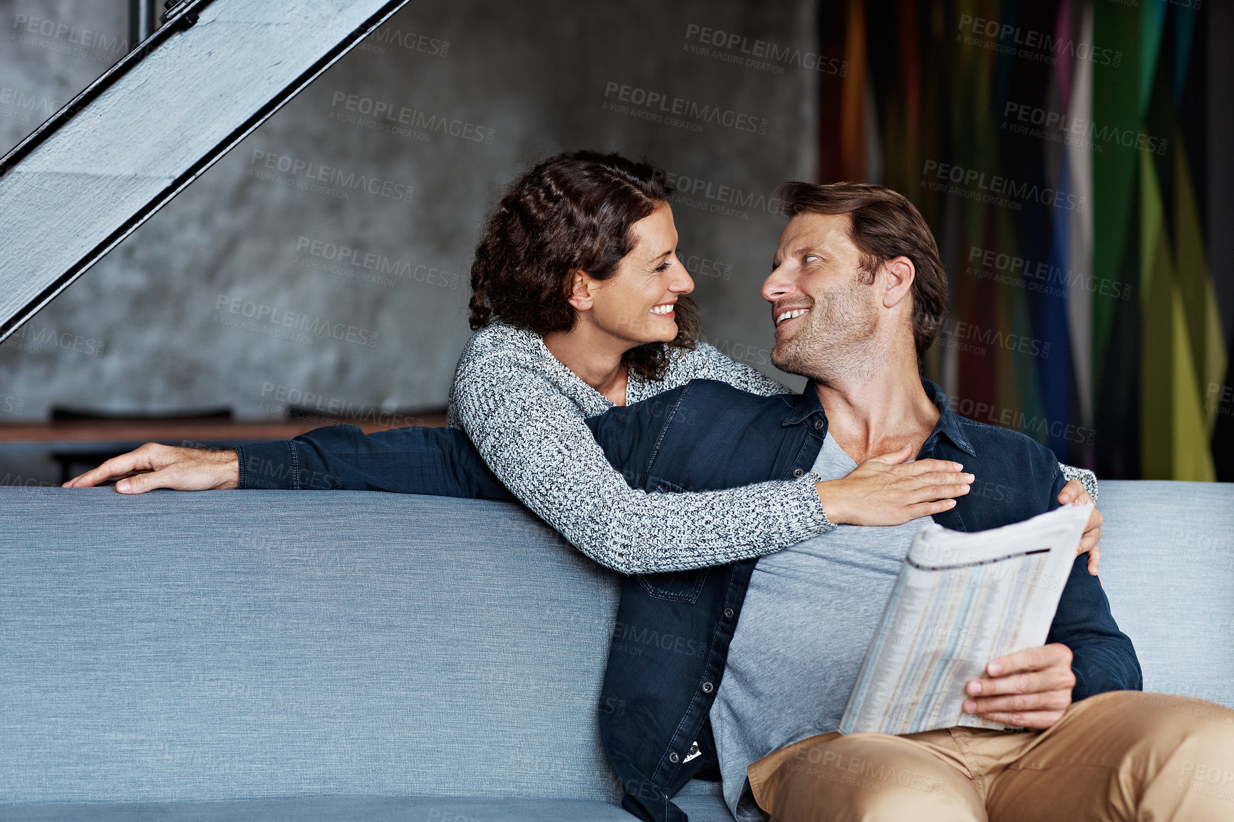 Buy stock photo Couple, newspaper and happy with hug on sofa for bonding together, healthy marriage or morning news. Love, woman and mature man embrace in home for relationship, connection or talk with article print