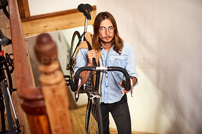 Buy stock photo Shot of a young man carrying his bike up the stairs
