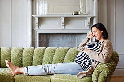 Buy stock photo Shot of a young pregnant woman relaxing on her sofa