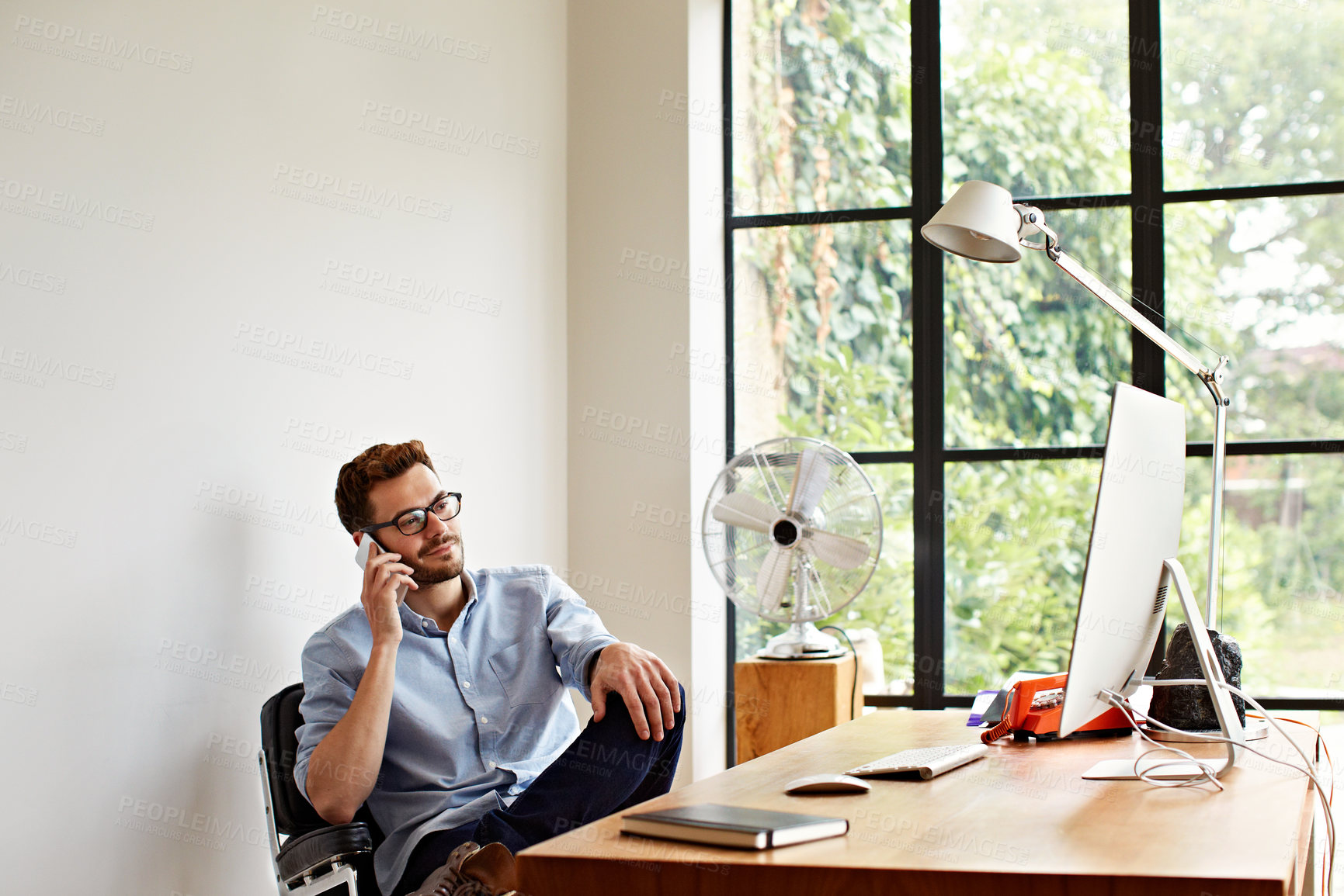 Buy stock photo Shot of a young man using his cellphone while working in his home office