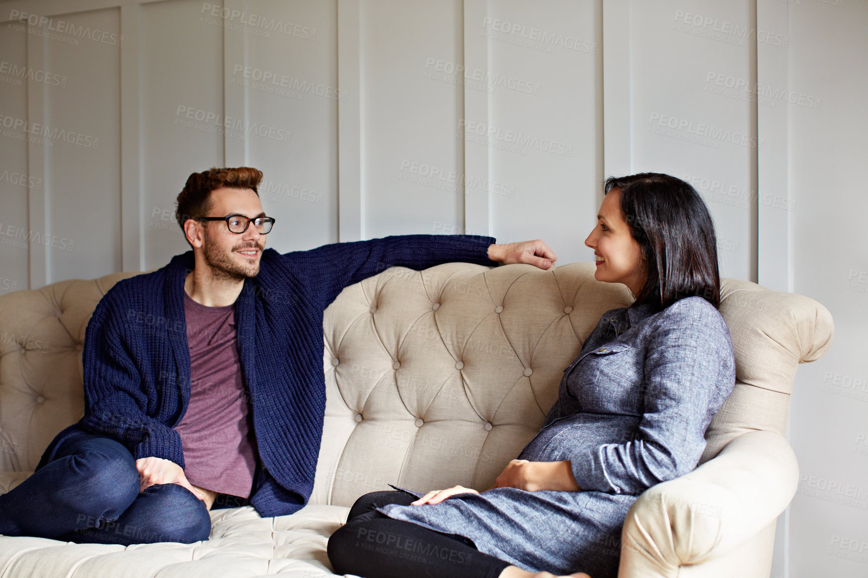 Buy stock photo Couple, smile and pregnant woman relax in living room for bonding together and support for wellness. Happy, people and rest in home with pregnancy, relationship and family planning for childcare.