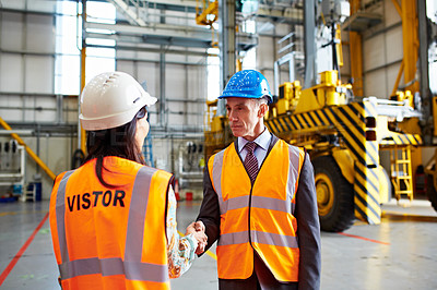 Buy stock photo Shot of two warehouse workers shanking hands together inside of a large warehouse