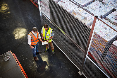 Buy stock photo High angle shot of two warehouse workers standing in a large warehouse