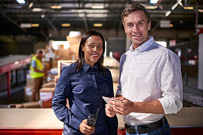 Buy stock photo Portrait of two coworkers standing together in a large distribution warehouse