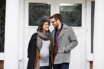 Buy stock photo Short of a pregnant woman and her husband standing on their front porch in autumn