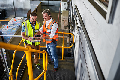 Buy stock photo Shot of two warehouse workers standing on stairs using a digital tablet