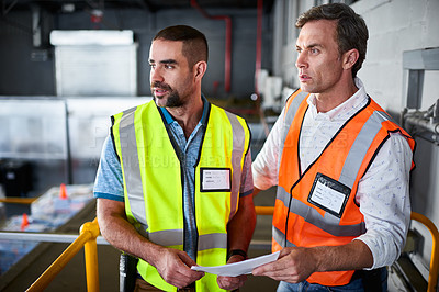 Buy stock photo Shot of two warehouse workers standing on stairs discussing papework