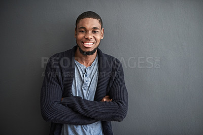 Buy stock photo Studio portrait of a smiling young man standing with his arms crossed against a gray background