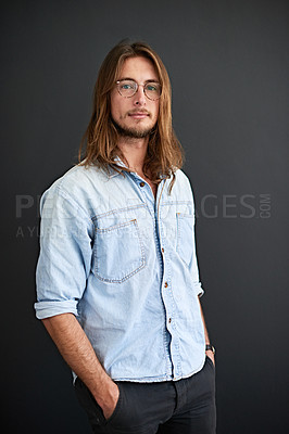 Buy stock photo Studio portrait of a young man standing with his hands in his pockets against a gray background