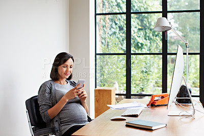 Buy stock photo Shot of a pregnant women using her phone while working in her home office