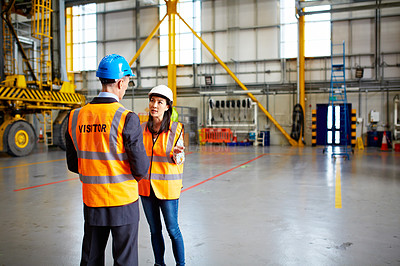 Buy stock photo Shot of two workers talking together while standing in a warehouse