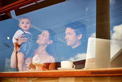 Buy stock photo Shot of smiling couple and their little girl standing in the window of their bakery