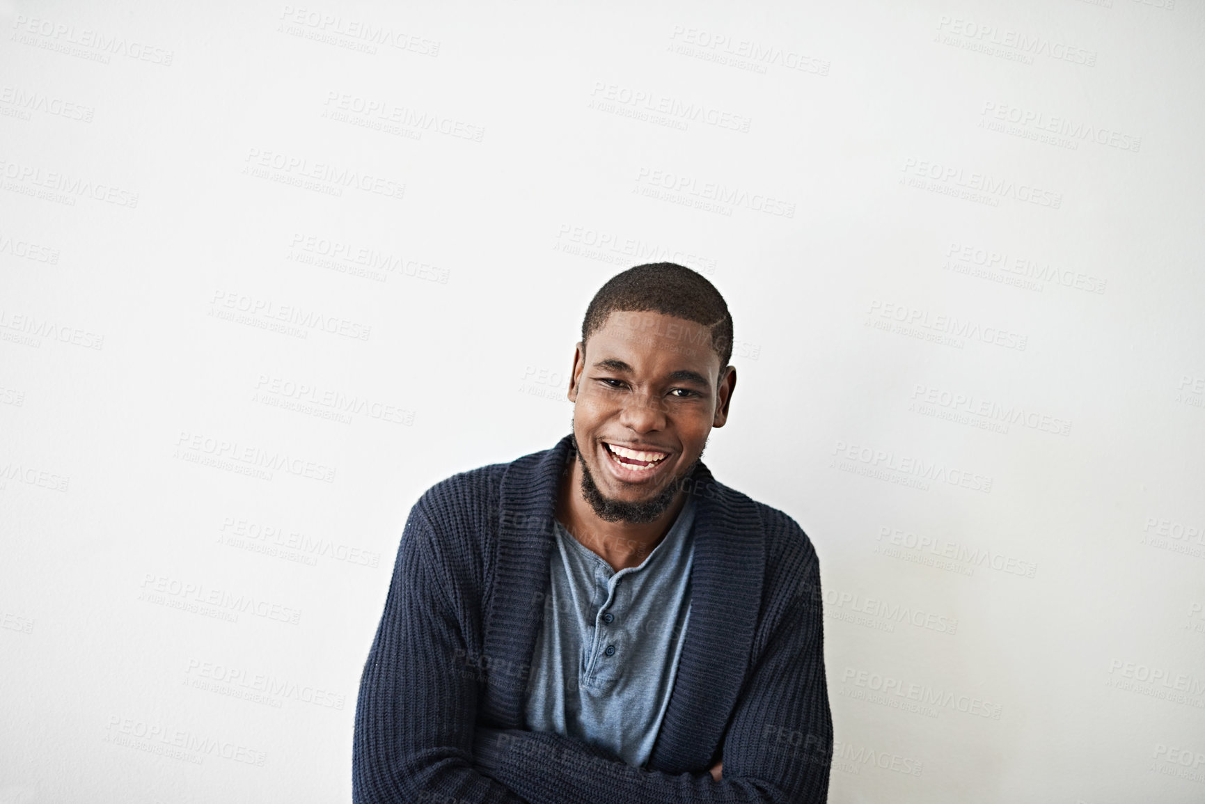 Buy stock photo Studio portrait of a smiling young man standing with his arms crossed against a gray background