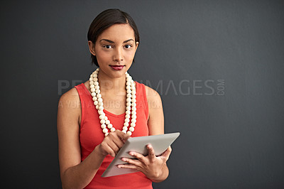 Buy stock photo Studio portrait of a young woman using a digital tablet against a gray background