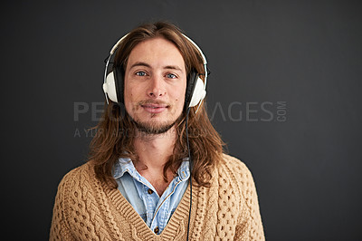 Buy stock photo Studio portrait of a young man listening to music on headphones against a gray background