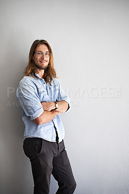 Buy stock photo Studio portrait of a smiling young man standing with his arms crossed against a gray background