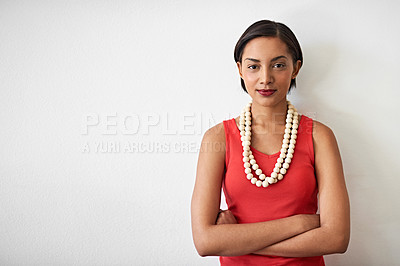 Buy stock photo Studio portrait of a smiling young woman standing with her arms crossed against a gray background