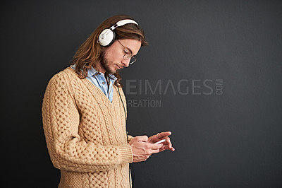 Buy stock photo Studio shot of a young man listening to music on headphones against a gray background