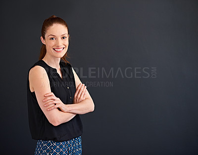 Buy stock photo Studio portrait of a smiling young woman standing with her arms crossed against a gray background