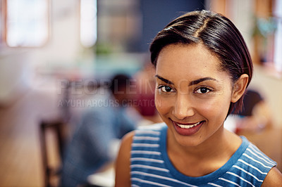Buy stock photo Portrait of a smiling young woman standing in an office with colleagues working in the background