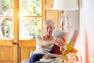 Buy stock photo Portrait of a smiling mature woman relaxing on a chair at home with a glass of wine