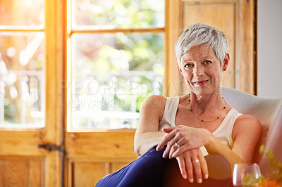 Buy stock photo Portrait of a smiling mature woman relaxing on a chair at home with a glass of wine