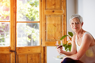 Buy stock photo Portrait of a smiling mature woman relaxing on a chair at home with a glass of wine
