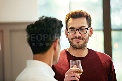 Buy stock photo Shot of two friends talking together and drinking wine while standing in the kitchen at home