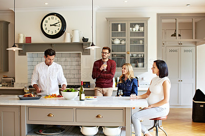Buy stock photo Shot of a group of friends talking and drinking wine while preparing a meal together