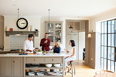 Buy stock photo Shot of a group of friends talking and drinking wine while preparing a meal together