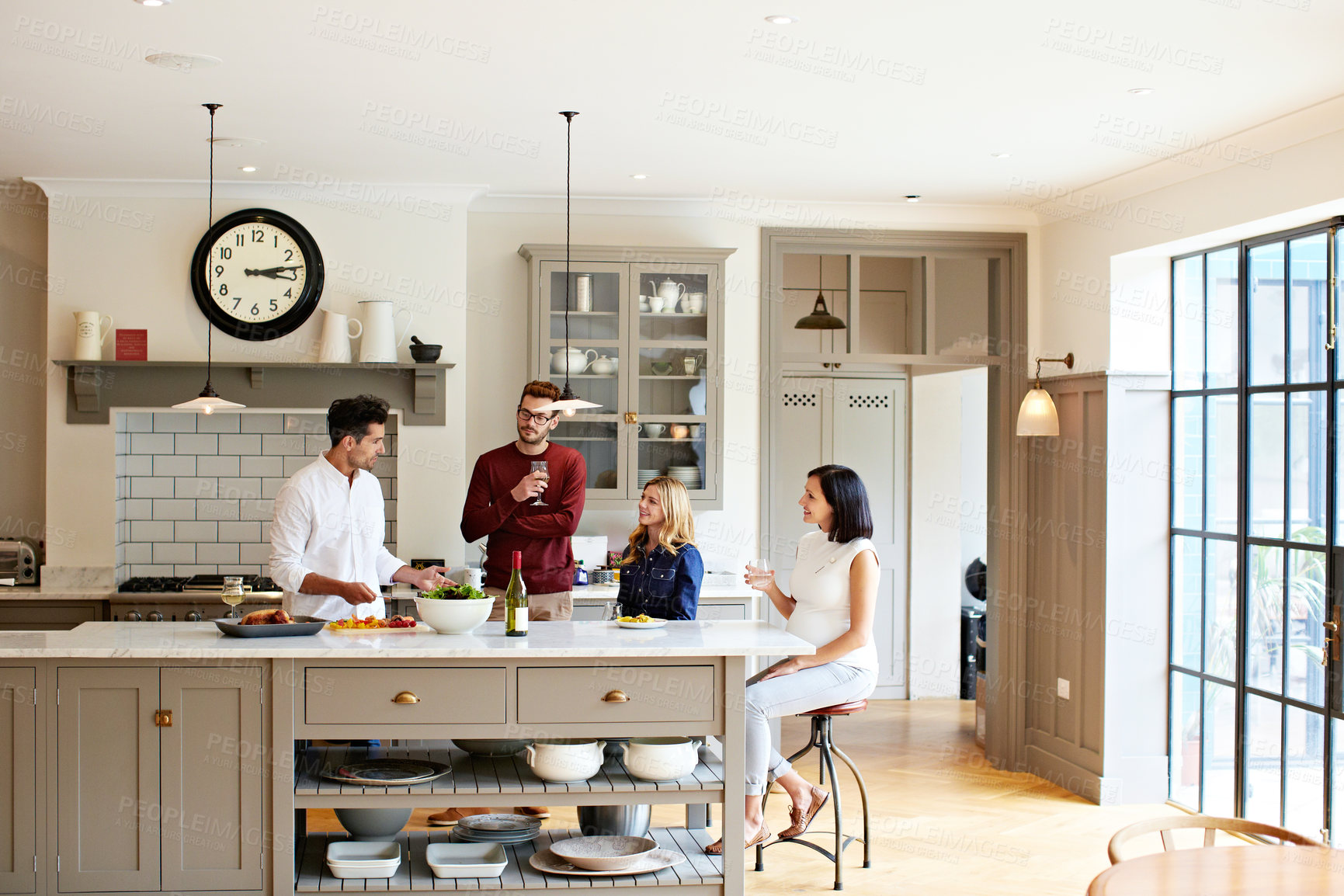 Buy stock photo Shot of a group of friends talking and drinking wine while preparing a meal together