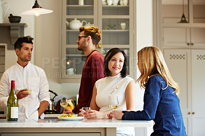 Buy stock photo Shot of a group of friends talking and drinking wine while preparing a meal together