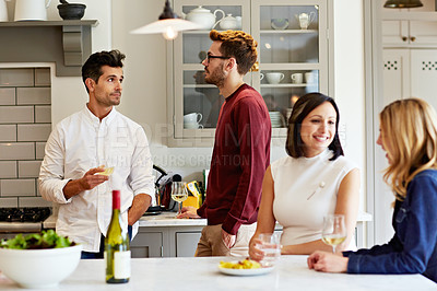 Buy stock photo Shot of a group of friends talking and drinking wine while preparing a meal together